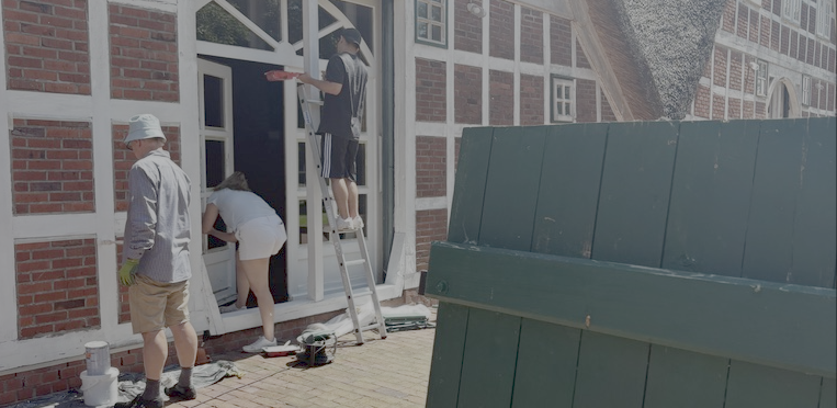 Freiwillige streichen die Außenfassade des Stall